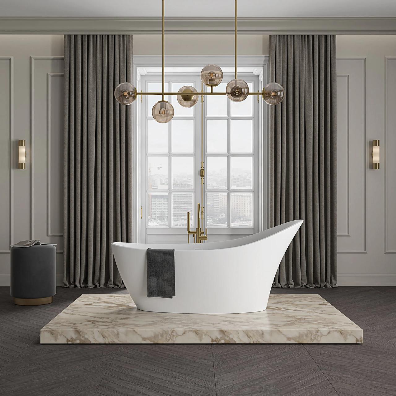 A strictly symmetrical view of a luxurious 3d bathroom. In the center, a white curved freestanding bathtub with a dark grey towel draped over the side sits on a raised light marble platform above a dark wooden floor. Behind the tub, a large window is framed by heavy grey curtains and light grey paneled walls. A modern brass chandelier with glass globes hangs above, matching the brass floor-mounted faucet and wall sconces. A small grey cylindrical pouf sits to the left.