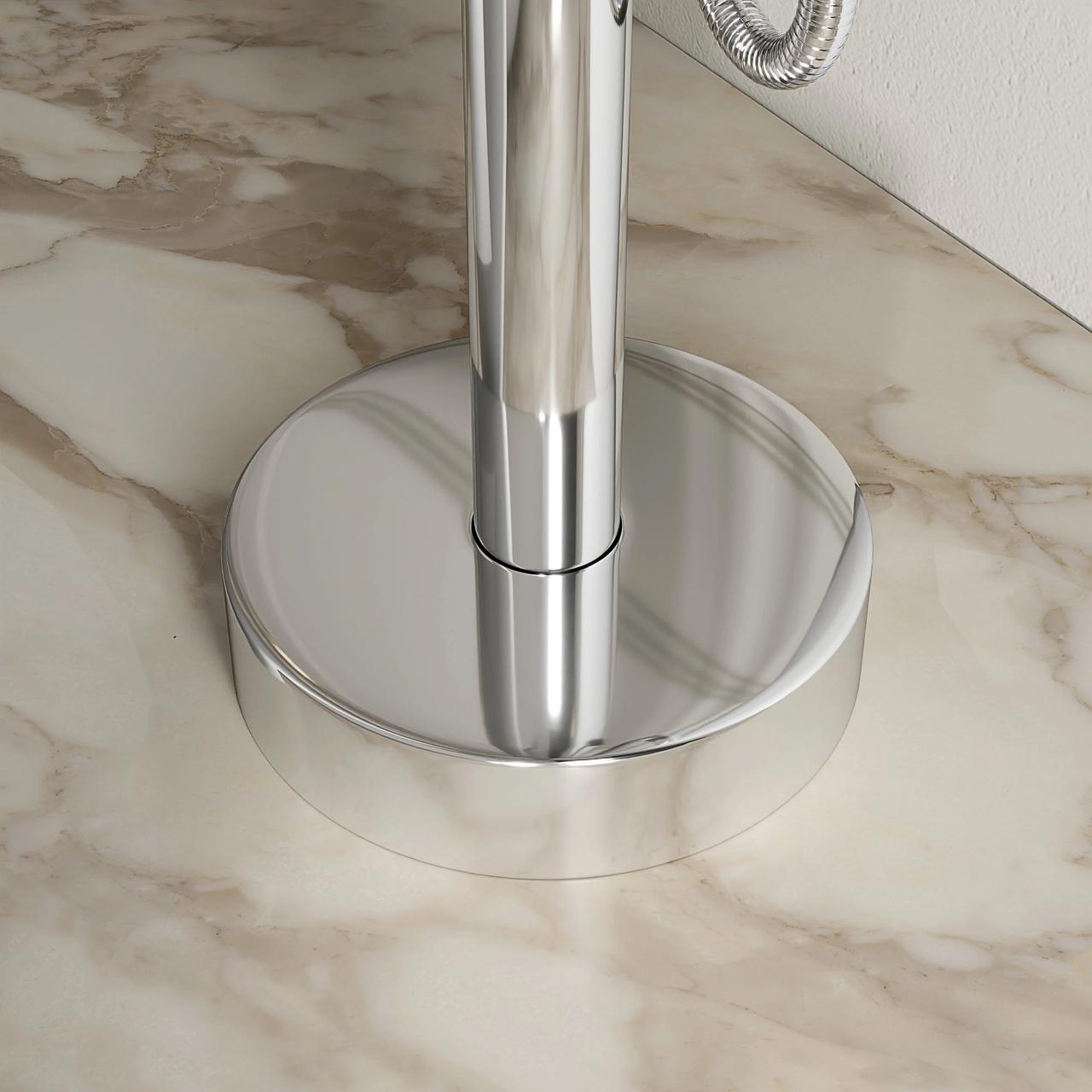 A detailed close-up of a reflective chrome baseplate for a freestanding 3d faucet, mounted on a light veined marble floor. The polished metal sharply reflects the surrounding floor texture and lighting.