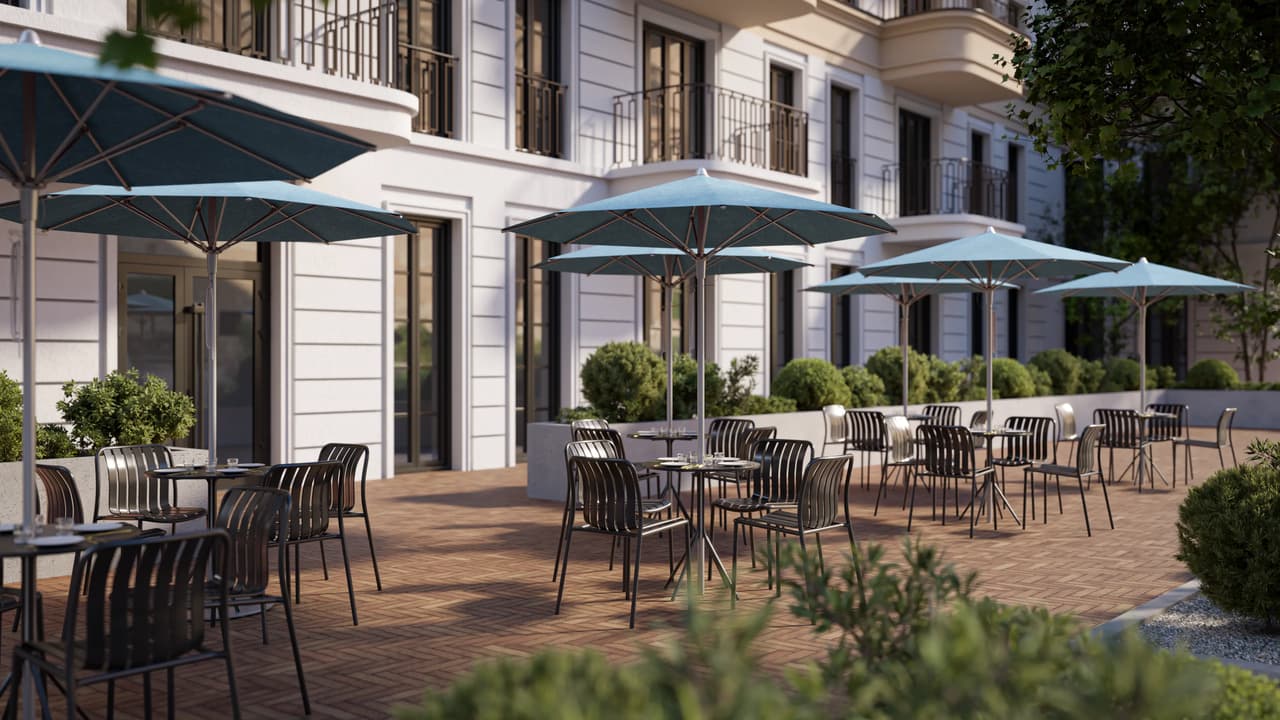 Outdoor restaurant patio seating area with round tables, black metal chairs, and light grey patio umbrellas in front of a modern classic building facade