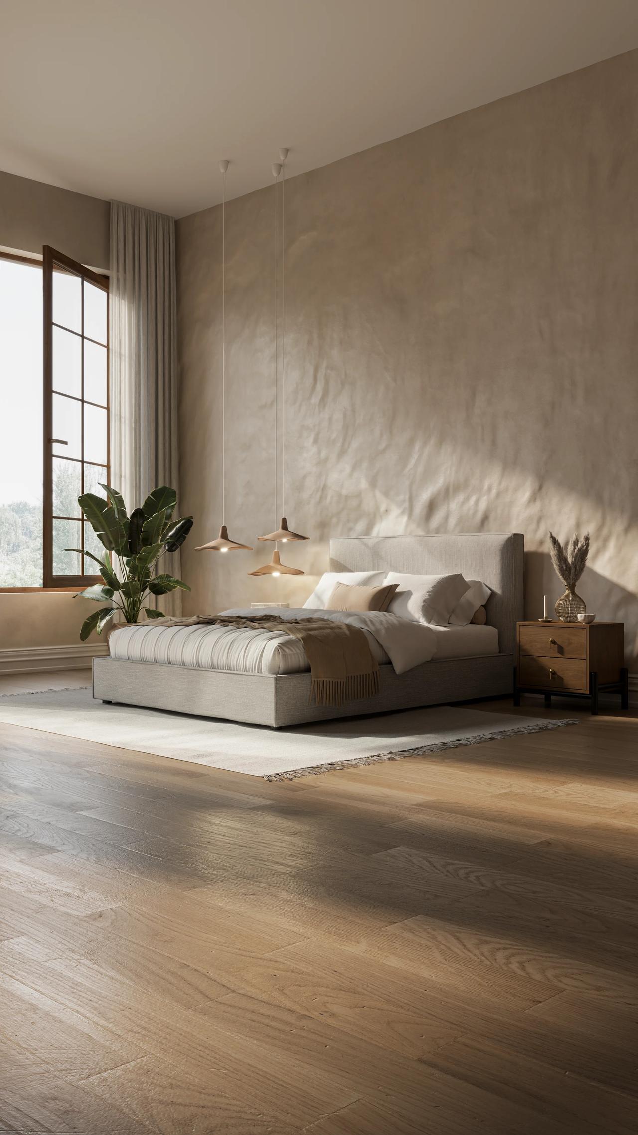 A spacious, sunlit cgi bedroom interior with warm wooden flooring and a textured accent wall. A low grey upholstered bed sits on a light rug, framed by a wooden nightstand, unique pendant lights, and natural light from a large window.