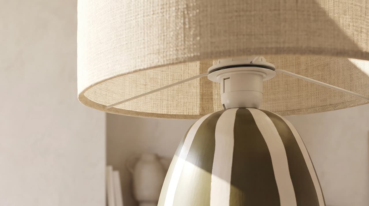 Detailed AI product visualization close-up of a striped ceramic table lamp with a woven linen shade.