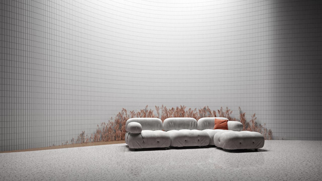 Tufted grey sectional sofa on terrazzo floor in front of a curved white tile wall with dried wheat stalks inside an abstract environment.
