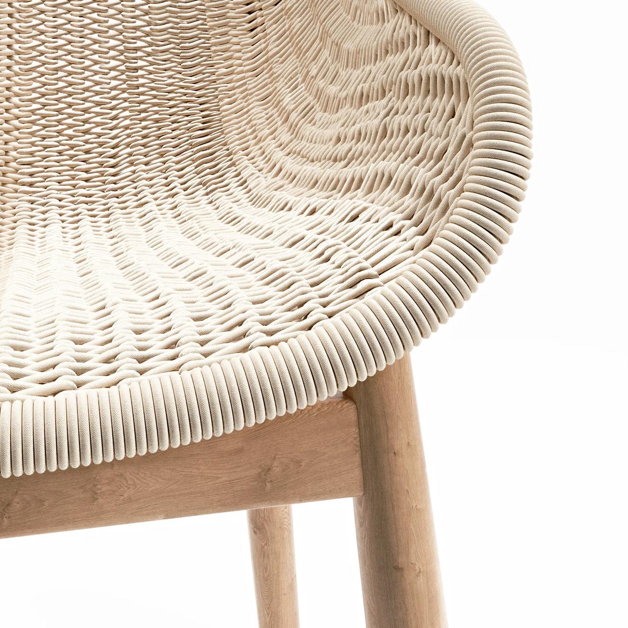 Detailed close-up of a light beige woven rope armchair with wooden legs on a white background, showcasing highly realistic 3d furniture rendering.