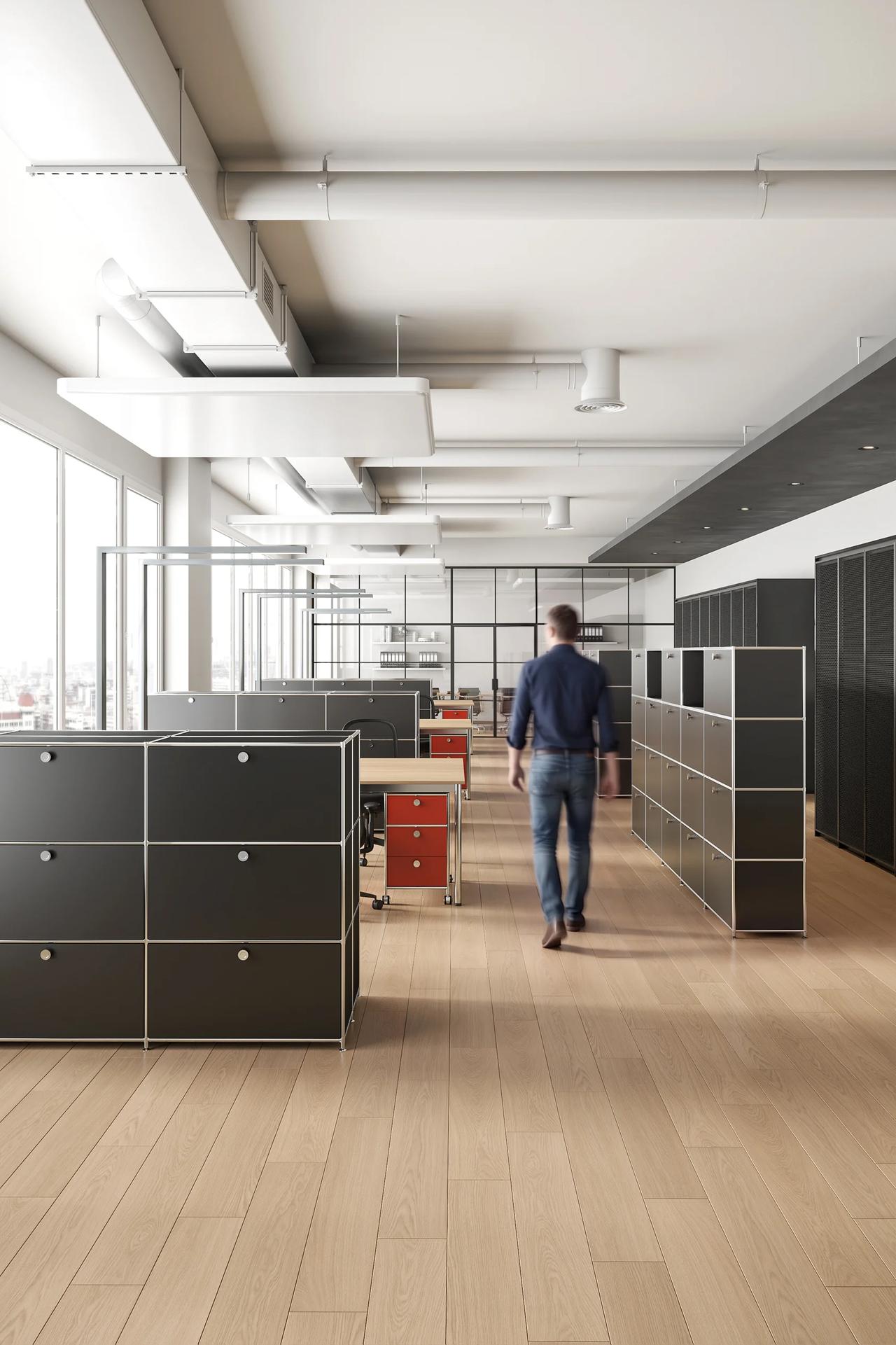 Vertical shot of a modern open office environment showcasing black modular shelving units that efficiently organize the work areas.