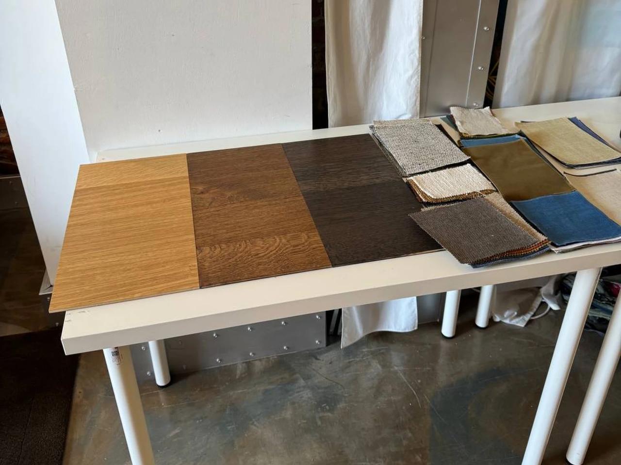 Various wood finishes and fabric upholstery material swatches laid out on a white desk for interior design and furniture selection