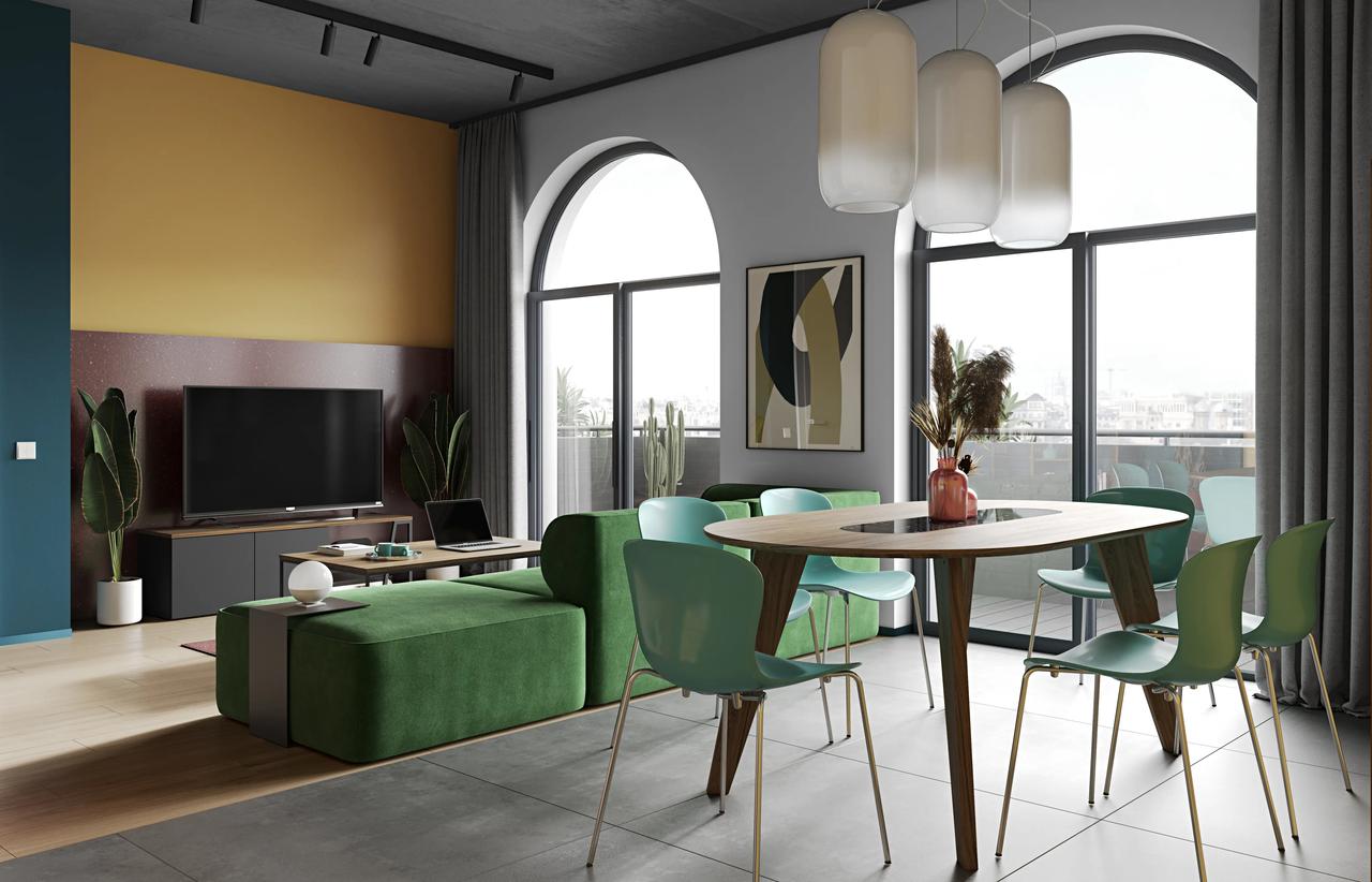 A spacious modern open-plan interior bathed in natural light from large black-framed arched windows. The foreground dining area features an oval wood table with green modern chairs and three frosted glass pendant lights, smoothly transitioning into a living area with a large green modular sofa and a dark red accent TV wall.
