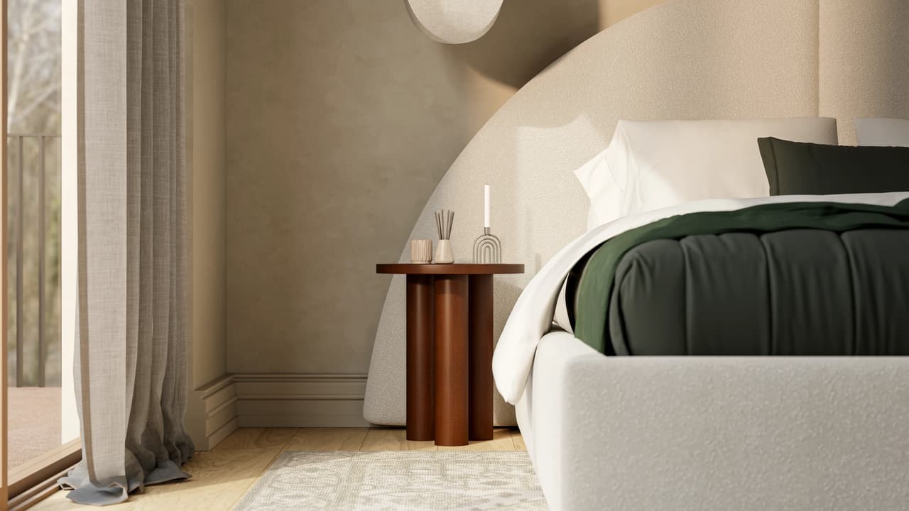 A cozy 3d bedroom corner featuring a white upholstered bed with a thick dark green duvet. Next to it, a unique cylindrical terracotta side table holding a candle is softly lit by natural light from a window with sheer linen curtains.