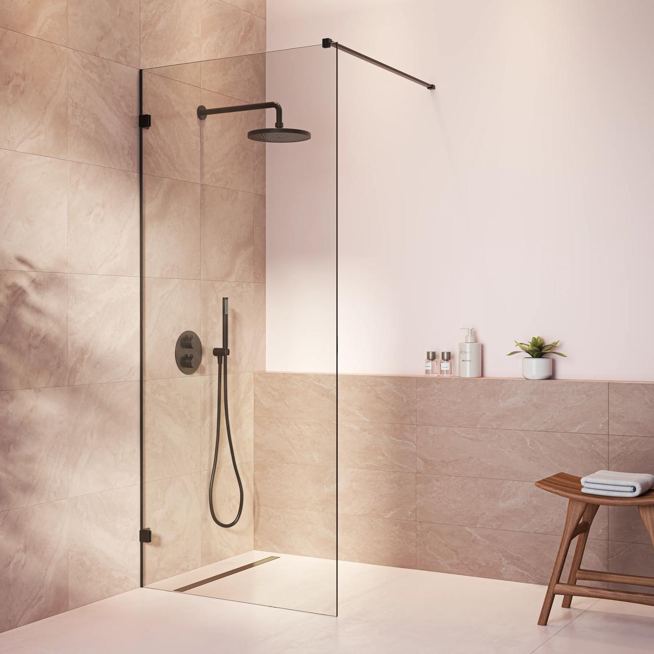 Modern walk-in shower enclosure with a clear glass partition, matte black rain shower head and hand spray, against warm beige stone tiles