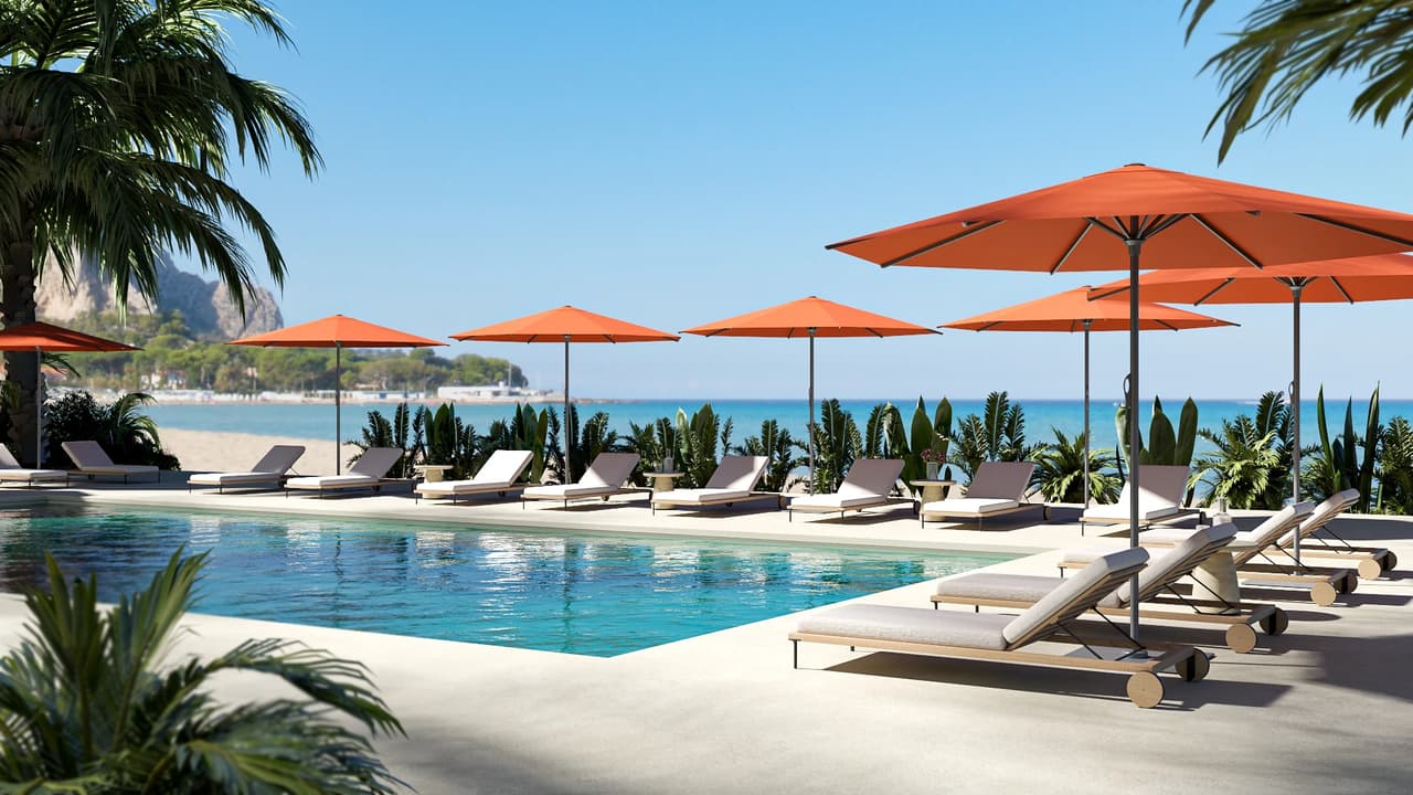 Rows of beige sun loungers and bright orange 3d umbrellas line a pristine swimming pool at a tropical beach resort. Palm trees and a calm blue ocean complete the sunny background.