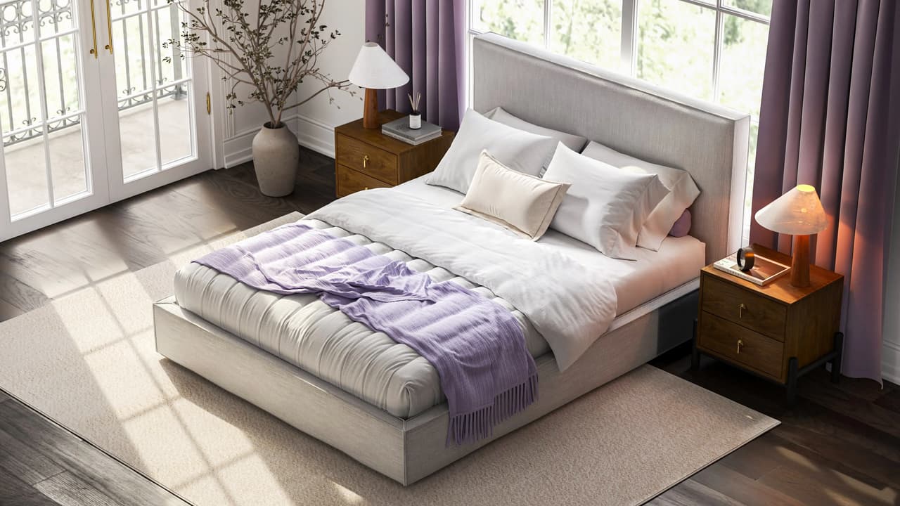 Top-down perspective of a bright bedroom centered around a light grey upholstered bed with white bedding and a fringed purple throw. The bed sits on a beige rug between two wooden nightstands with lit lamps, near a large glass door and purple drapes.