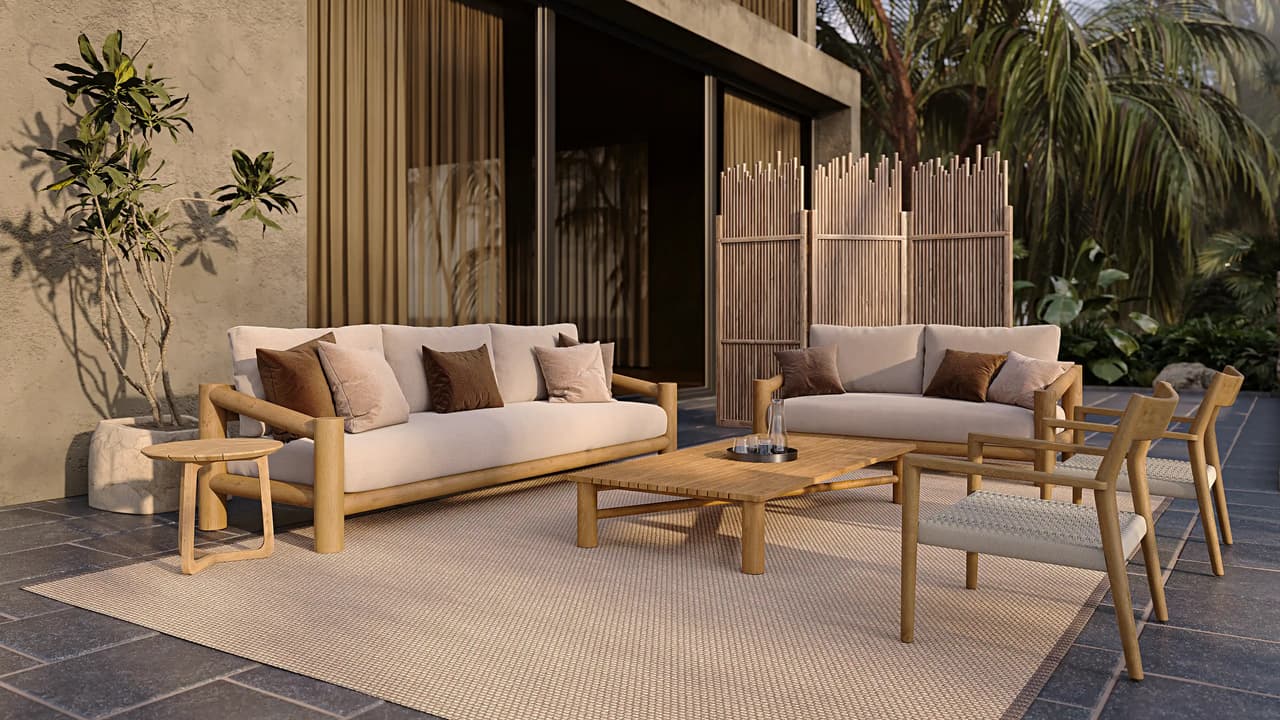 A sunlit outdoor cgi terrace featuring a wooden lounge furniture set with a large sofa, a loveseat, and two armchairs with woven seats arranged around a slatted coffee table. The set rests on a large beige rug. In the background, there is a bamboo folding screen, tropical plants, and a modern house with large dark glass doors. Warm sunlight casts distinct plant shadows on the textured wall to the left.